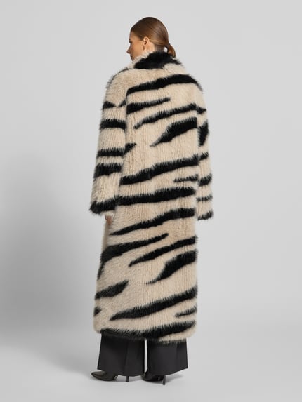 Frauenmodel trägt Mantel aus Kunstfell im Allover-Look von Beaumont Amsterdam in Creme mit schwarzen Streifen, strukturierte Oberfläche, Ganzkörperansicht Rückansicht. Relaxed Fit, Reverskragen, Knopfverschluss, Rückenlänge 132 cm, Schulterbreite 57 cm, Brustweite 56 cm, Ärmellänge 53 cm.