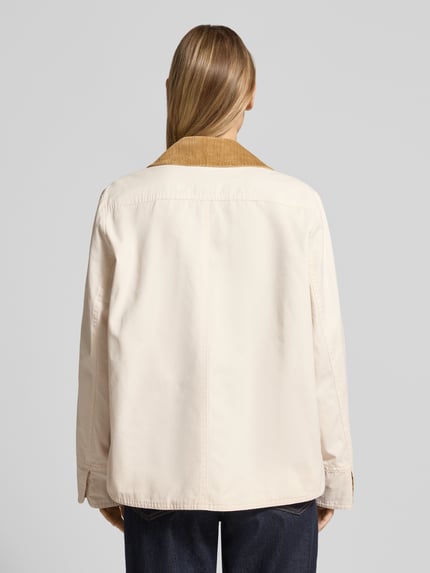 Vrouwenmodel draagt Jacke mit Umlegekragen und aufgesetzten Pattentaschen van WHITE LABEL in recht model met platte kraag, drukknoopsluiting, opgestikte klepzakken, ruglengte maat 36: 67 cm, schouderbreedte 44 cm, borstwijdte 53 cm, mouwlengte 63 cm, lichte kleur, gladde textuur, donkere kraag, Ganzkörperansicht Rückansicht.