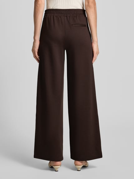 Frauenmodel trägt Hose mit weitem Bein Modell 'KATE' von ICHI, unifarben, elastischer Bund, Material-Mix, Gesäßtasche, Ganzkörperansicht Rückansicht.