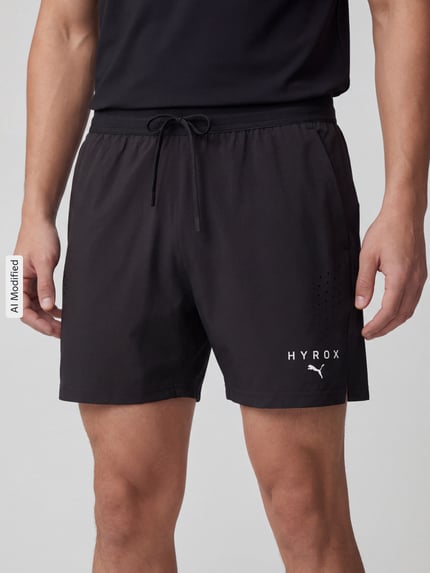 Männermodel trägt schwarze Regular Fit Sportshorts mit Label-Print von PUMA Performance, dezenter Glanz, glatte Textur, Nahaufnahme Oberkörper.