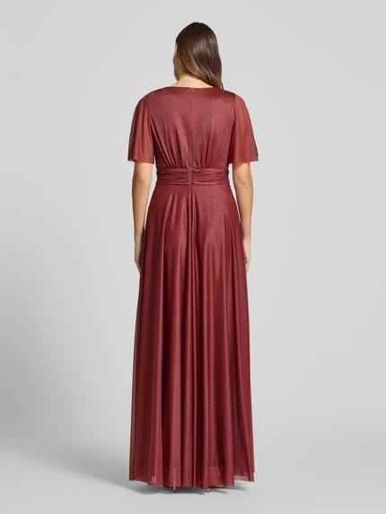 Frauenmodel trägt schimmerndes Maxikleid mit V-Ausschnitt und Taillenband von Christian Berg Cocktail aus Mesh in A-Linie, Ganzkörperansicht Rückansicht. Rückenlänge bei Größe 36: 149 cm, Brustweite bei Größe 36: 35 cm, Ärmellänge bei Größe 36: 29 cm.