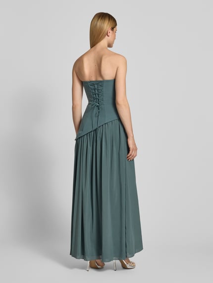 Frauenmodel trägt Cocktailkleid im Off-Shoulder-Look von Hey Kyla, Material-Mix mit Stretch-Anteil, Maxikleid, Figurbetont, Ganzkörperansicht Rückansicht.