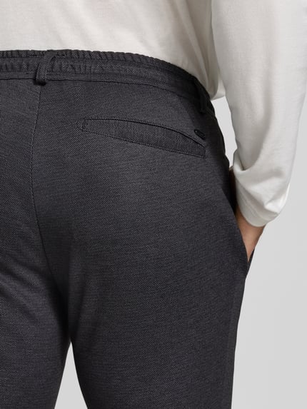 Männermodel trägt Tapered Fit Jogpants mit Viskose-Anteil Modell 'Phil' von Brax in Dunkelgrau, feine Struktur, Detailaufnahme, Herren Weite Hose von Brax.