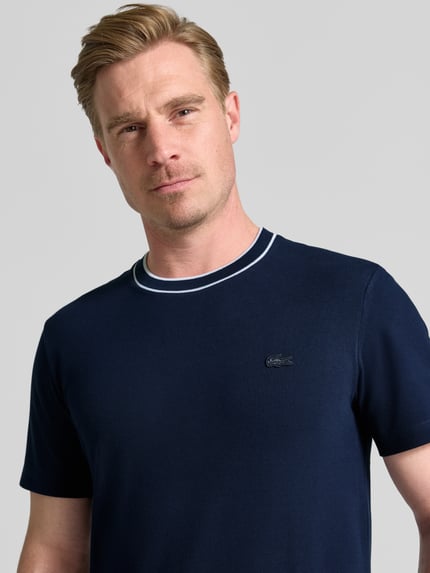 Męski model nosi Regular Fit T-Shirt aus Baumwoll-Mix Modell 'CREATOR' von Lacoste, granatowy kolor, gładka tekstura, męski t-shirt, Nahaufnahme Oberkörper.