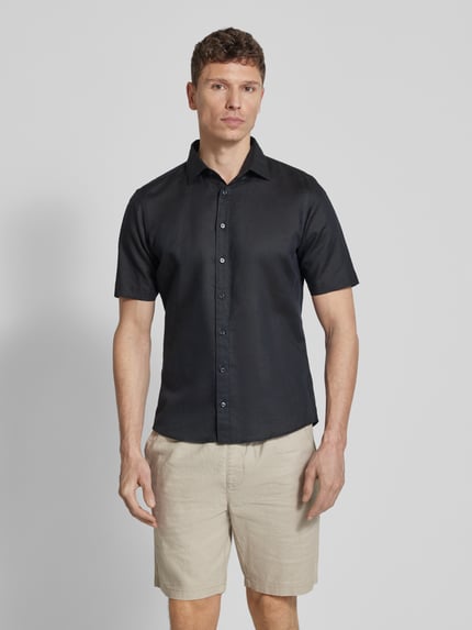 Männermodel trägt Slim Fit Freizeithemd aus Leinen-Mix von Jake*s, schwarzes Hemd mit Kentkragen, kurzärmelig, Ganzkörperansicht von vorne.