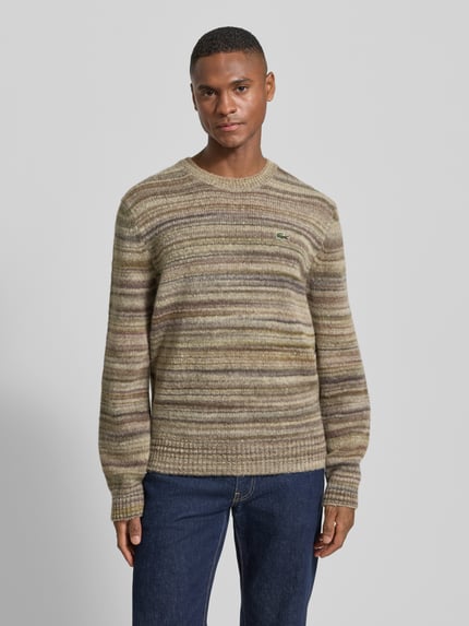 Männermodel draagt Regular Fit gebreide pullover uit wolmix van Lacoste in gemêleerde look met labelpatch, ronde hals, lange mouw; frontale opname bovenlichaam.