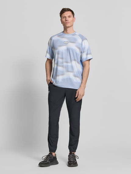 Männermodel trägt Regular Fit T-Shirt mit Logo-Applikation von EA7 Emporio Armani, hellblau mit weißen und blauen Streifen, Rundhalsausschnitt, elastischer Material-Mix, Ganzkörperansicht von vorne.
