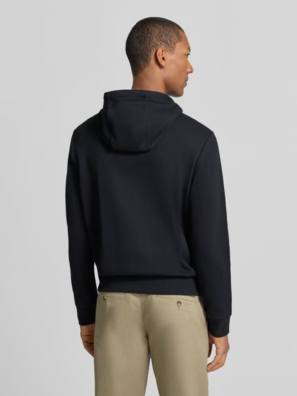 Männermodel trägt Regular Fit Strickjacke aus Baumwoll-Mix von Polo Ralph Lauren in Schwarz und Beige, Ganzkörperansicht Rückansicht. Herren Strickjacke von Polo Ralph Lauren