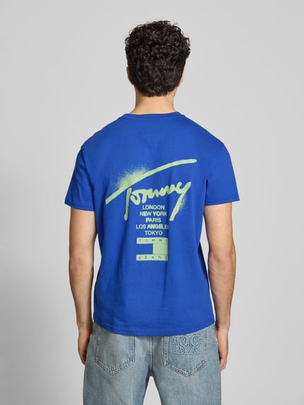 Männermodel trägt Regular Fit T-Shirt aus reiner Baumwolle von Tommy Jeans, Optik: Unifarben, Label-Schriftzug, Ganzkörperansicht Rückansicht.
