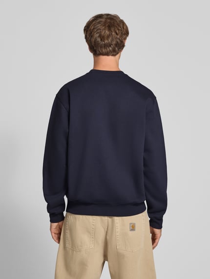 Männermodel trägt Regular Fit Sweatshirt aus Baumwoll-Mix mit Logo-Stickerei von Carhartt Work In Progress in Dunkelblau, Ganzkörperansicht Rückansicht. Baumwoll-Mix, gerippte Abschlüsse, langärmeliges Design, überschnittene Schultern, Rundhalsausschnitt, Rückseite sichtbar.