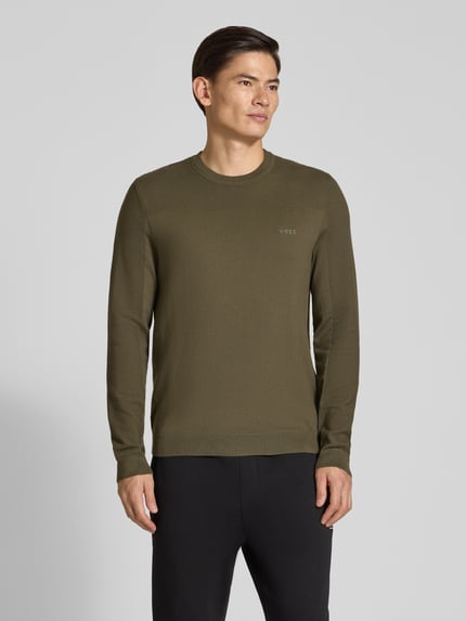 Männermodel trägt Pullover mit Logo-Schriftzug von BOSS in Olive, Regular Fit, Rundhals, Strickstruktur, Ganzkörperansicht von vorne.