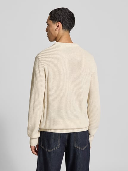 Männermodel trägt Pullover mit gerippten Abschlüssen Modell 'ONSJONAS' von ONLY in Strickoptik, Struktur, Farbe Creme, Ganzkörperansicht Rückansicht.