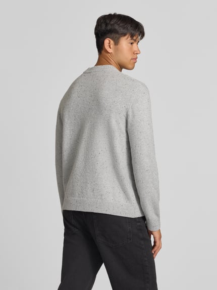 Männermodel trägt Regular Fit Strickpullover mit Rundhalsausschnitt von JACK & JONES in Hellgrau, gerippte Abschlüsse, Rückenansicht.