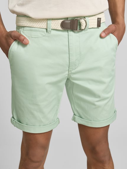 Männermodel trägt Bermudas mit Gürtel und Eingrifftaschen von MCNEAL in Mintgrün, Straight Fit, Nahaufnahme Oberkörper. Baumwoll-Mix mit Stretch, sichtbare seitliche Eingrifftaschen, Gürtel und Saum mit Aufschlag.