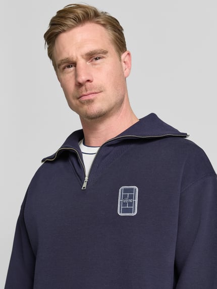 Mężczyzna nosi Loose Fit Troyer aus Baumwoll-Mix Model 'Tennisc' od Lacoste, granatowy kolor, tekstura gładka, zbliżenie na górną część ciała, Herren Troyer von Lacoste.