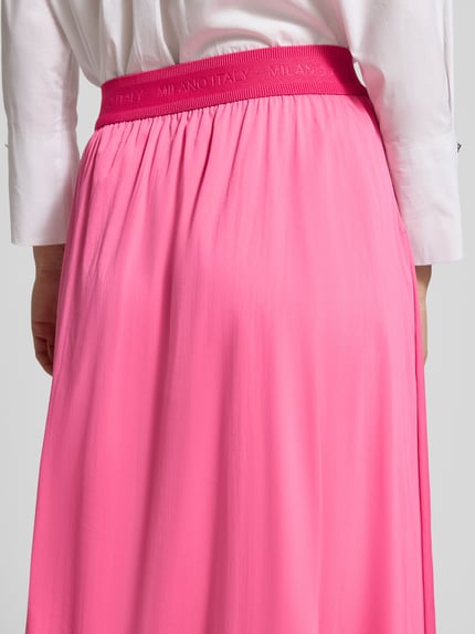 Frauenmodel trägt Midirock mit elastischem Bund Modell 'SNOS' von Milano Italy in leuchtendem Pink, Baumwoll-Mix mit Stretch-Anteil, Detailaufnahme Rückansicht.