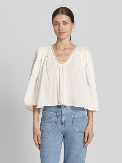 Frauenmodel trägt Cropped Bluse mit 3/4-Arm Modell 'ISMARA' von Drykorn, Cremefarbe, Baumwoll-Viskose-Mix, V-Ausschnitt, Ganzkörperansicht von vorne.