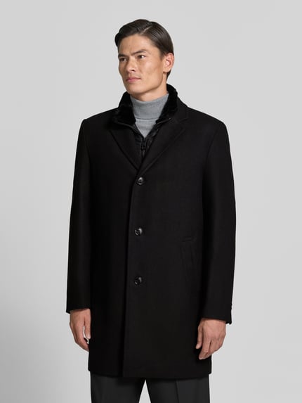 Männermodel trägt Regular Fit Mantel aus Woll-Mix von HECHTER PARIS in Schwarz, glatte Textur, Knopfleiste, Ganzkörperansicht von vorne, Herren Mantel.