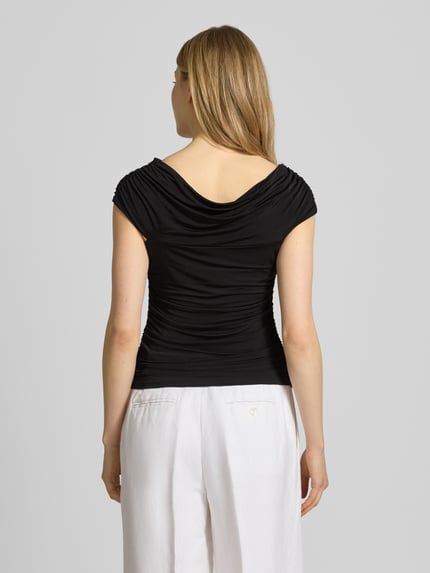 Männermodel trägt damski t-shirt z mieszanki wiskozy i elastanu, krój slim fit, odkryte ramiona, drapowania Gestuz T-Shirt mit Drapierungen Modell 'laily', długość tyłu w rozmiarze S: 60 cm, czarny kolor, gładka tekstura, całkowity widok z tyłu