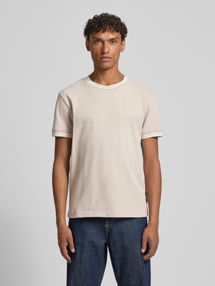 Männermodel trägt T-Shirt mit Kontraststreifen Modell 'Jose' von JOOP! Collection aus Baumwoll-Elasthan-Mix in Regular-Fit, Rundhalsausschnitt, dezente Kontraststreifen, Rückenlänge 67 cm bei Größe M, helle Farbe, glatte Textur, Ganzkörperansicht von vorne.
