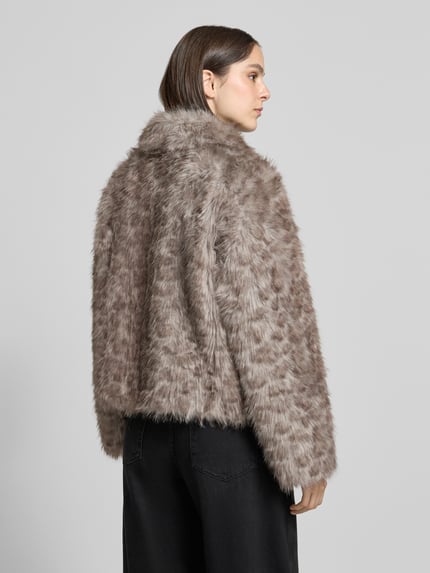 Frauenmodel trägt Webpelzjacke mit Umlegekragen von VERO MODA, melange Optik, strukturierte Musterung, cropped Länge, langarm, Ganzkörperansicht Rückansicht.