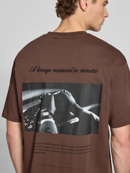 Männermodel trägt Oversized T-Shirt aus reiner Baumwolle Modell 'Devrolo' von HUGO in Braun mit Print, Ganzkörperansicht Rückansicht, Herren T-Shirt von HUGO