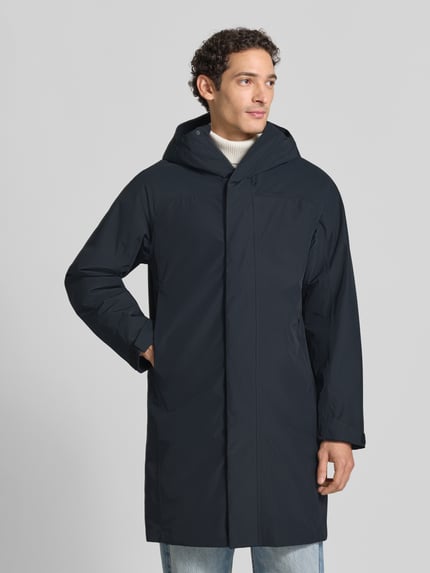 Męski model ma na sobie czarną parkę o kroju regular fit z kapturem Peak Performance Regular Fit Parka mit Kapuze Model 'Treeline HIPE', zamek błyskawiczny zakryty, Długość tyłu w rozmiarze M: 99 cm, szerokość ramion w rozmiarze M: 54 cm, szerokość klatki piersiowej w rozmiarze M: 60 cm, długość rękawów w rozmiarze M: 61 cm, widok całej sylwetki z przodu
