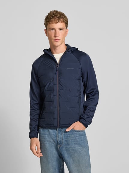 Männermodel trägt dunkelblaue Hybrid Jacke mit Kapuze Modell 'PERFECT' von JACK & JONES, strukturierte Oberfläche, Ganzkörperansicht von vorne. Gerader Schnitt, Reißverschluss, Logo-Print, seitliche Reißverschlusstaschen, Rückenlänge 67 cm, Schulterbreite 44 cm, Brustweite 51 cm, Ärmellänge 69 cm.