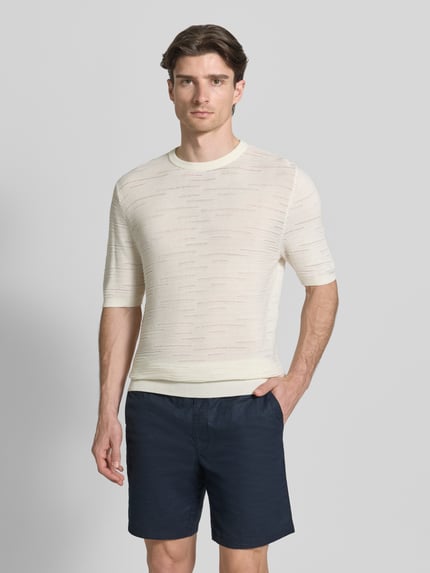 Männermodel trägt Strickshirt aus Baumwolle von Antony Morato in Creme, gerader Schnitt, Halbarm, gerippte Abschlüsse, Ganzkörperansicht von vorne.