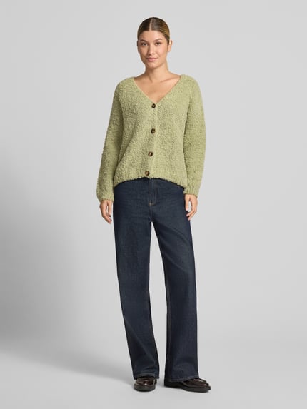 Frauenmodel trägt Cardigan mit V-Ausschnitt Modell 'So44fia' von ZABAIONE in Hellgrün, grobe Textur, Knopfleiste, Ganzkörperansicht von vorne. Material-Mix mit Viskose-Anteil, gerader Schnitt, Rückenlänge 56 cm, Ärmellänge 47 cm.