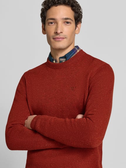 Männermodel trägt Pullover aus Woll-Seide-Mix mit Rundhalsausschnitt Modell 'TISBURY' von BARBOUR in Rostrot, Stricktextur, Nahaufnahme Oberkörper. Unifarbener Herren Strickpullover mit geripptem Rundhals, langen Ärmeln und gerippten Abschlüssen.