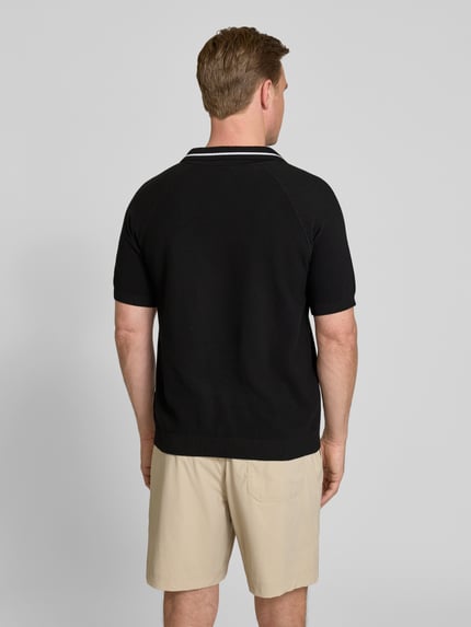 Männermodel trägt Regular Fit Poloshirt aus Strick von BOSS Green in Strickoptik, reine Baumwolle, Polokragen, Kurzarm, Ganzkörperansicht Rückansicht.