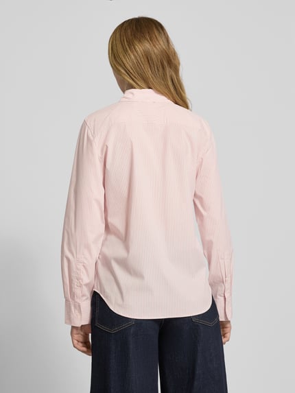 Vrouwenmodel draagt Regular Fit Hemdbluse aus Baumwoll-Mix van Tommy Hilfiger met fijn allover-streepmotief, lange mouwen, popeline structuur, merklogo, afgeronde zoom. Ganzkörperansicht achteraan.