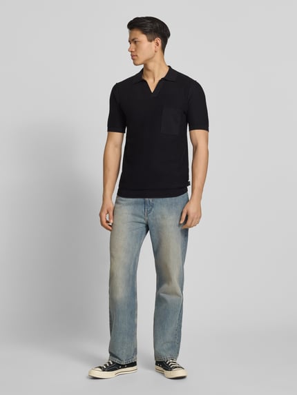 Männermodel trägt Slim Fit Poloshirt in Strick-Optik von Replay in Schwarz, reine Baumwolle, V-Ausschnitt, gerippte Abschlüsse, Ganzkörperansicht von vorne.