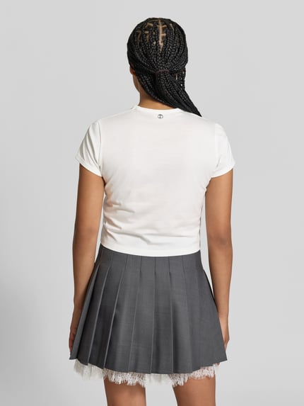 Kobiece model prezentuje Regular Fit T-Shirt mit Statement-Print od Rabanne z czystej bawełny, okrągły dekolt, krótki rękaw, długość tyłu w rozmiarze S: 46 cm, widok całej sylwetki z tyłu.