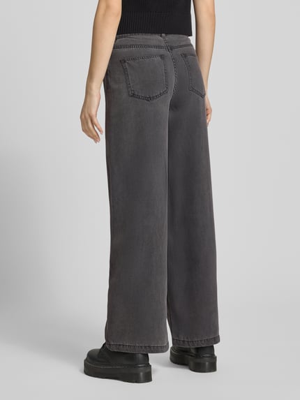 Modelka nosi Wide Leg Jeans aus Lyocell-Mix Modell 'SMIDI' od Pieces, denim, krój wide leg, 5 kieszeni, szlufki, zapięcie na guzik i zamek, szary kolor, widok całej sylwetki z tyłu.