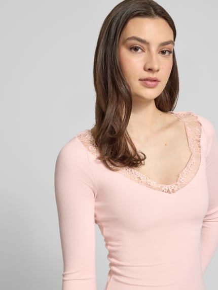 Vrouwenmodel draagt Longsleeve met V-hals en kant van Gina Tricot, katoenmix met modal, slim fit, fijnrib, ruglengte maat S 53 cm, nahaufnahme bovenlichaam.