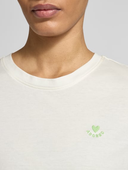 Vrouwenmodel draagt Regular Fit T-Shirt uit pure katoen van s.Oliver RED LABEL, effen, met borduursel, ronde hals, korte mouw, detailopname bovenlichaam.