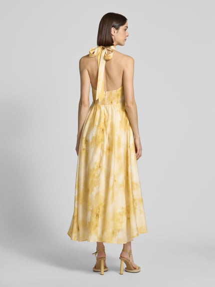 Frauenmodel trägt Damen Midikleid aus Lyocell-Mix mit Eingrifftaschen Modell 'FIE' von Copenhagen Muse im Allover-Look in Gelb, A-Linie, V-Ausschnitt, Ganzkörperansicht Rückansicht. Rückenlänge bei Größe S: 11 cm, Brustweite bei Größe S: 40 cm.