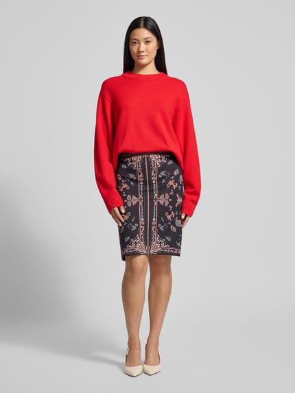 Frauenmodel trägt Knielanger Strickrock im Allover-Look von Marc Cain in schwarz-rot, Baumwoll-Viskose-Mix, Ganzkörperansicht von vorne.
