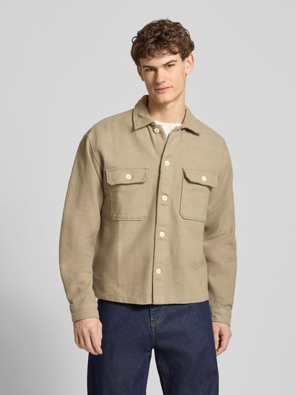 Męski model nosi Regular Fit Hemdjacke mit Strukturmuster Modell 'Upstate' od Jack & Jones, beżowa bawełna, kieszenie, krój regular fit, widok całej sylwetki z przodu.