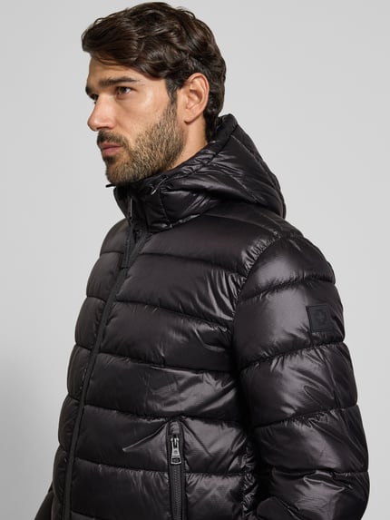 Männermodel trägt Regular Fit Steppjacke mit Storm Cuffs Modell 'BAVENO' von Strellson in Schwarz, glänzende Optik, Nahaufnahme Oberkörper.