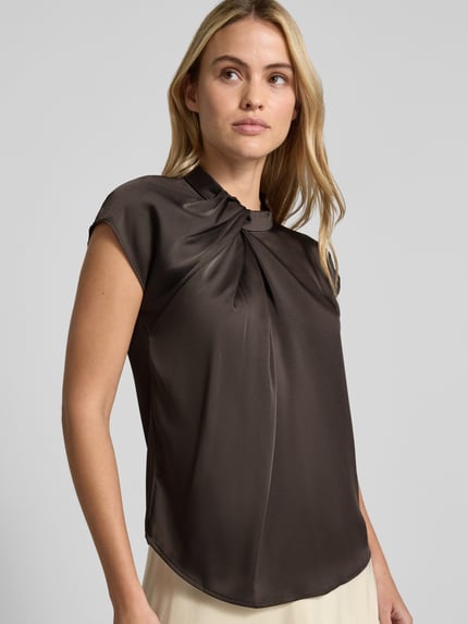 Modelka kobieca ma na sobie Blusentop aus Satin mit Knotendetail Modell 'Fleur Drapy' od Neo Noir, satynowy, krój regular fit, długość tyłu w rozmiarze 36: 59 cm, zdjęcie górnej części ciała z przodu.