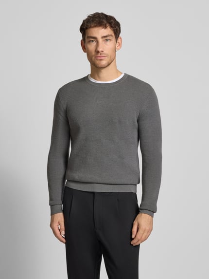 Männermodel trägt Strickpullover mit gerippten Abschlüssen Modell 'Connor' von Tiger Of Sweden in Grau, Woll-Baumwoll-Mix, Ganzkörperansicht von vorne.