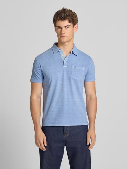 Männermodel trägt Slim Fit Poloshirt mit Brusttasche von Superdry aus Baumwoll-Leinen-Mix, Knopfleiste, Rückenlänge 67 cm, Ganzkörperansicht von vorne.