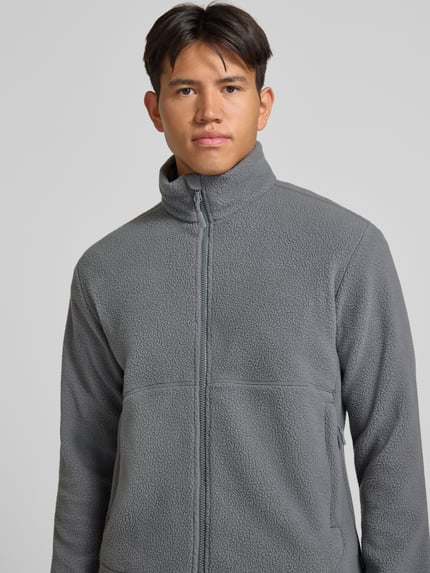 Mężczyzna nosi szarą kurtkę z polaru z krój regular fit, stójką, model 'JASON' od ONLY & SONS, detaliczne zbliżenie na górę.