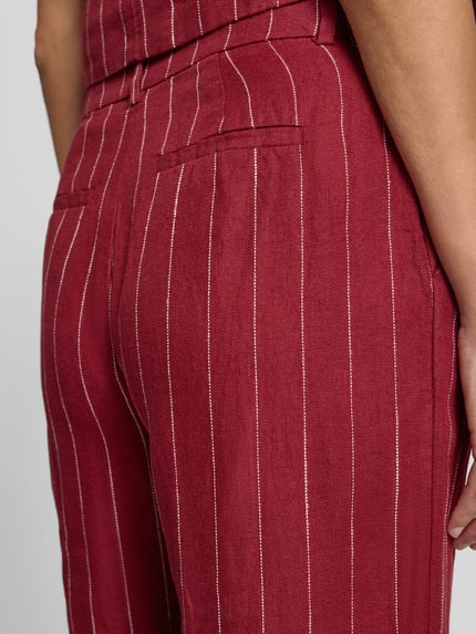Frauenmodel trägt Wide Fit Leinenhose mit Viskose-Anteil Modell 'Claritte' von MSCH Copenhagen im Leinen-Mix mit feinem Streifenmuster, Eingriff- und Gesäßtaschen, Detailaufnahme Rückansicht.