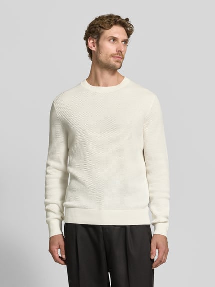 Männermodel trägt Regular Fit Pullover aus reiner Baumwolle Modell 'Lalex' von BOSS in Creme mit feiner Struktur, Ganzkörperansicht von vorne. Herren Pullover von BOSS.