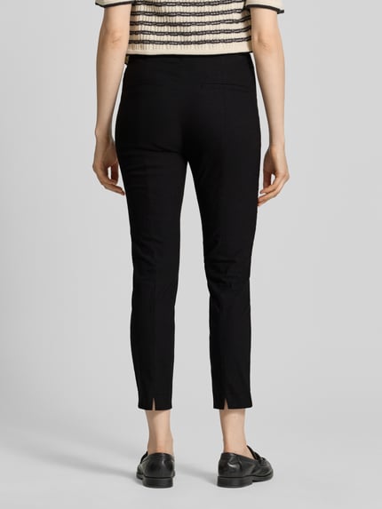 Frauenmodel trägt Slim Fit Stoffhose in verkürzter Passform von Christian Berg Woman, schwarze Farbe, elastischer Baumwoll-Mix, Ganzkörperansicht Rückansicht.