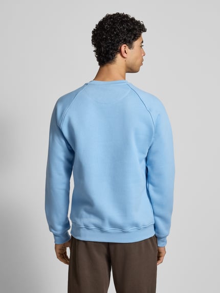 Männermodel trägt Sweatshirt mit Label-Stitching von adidas Originals in Hellblau, Baumwoll-Mix, lockerer Schnitt, gerippte Abschlüsse, Rundhalsausschnitt, Rückenlänge 70 cm, Ärmellänge 82 cm, Ganzkörperansicht Rückansicht.